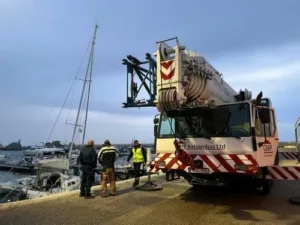 Boat in Paphos harbour damaged by strong winds, pulled out by crane