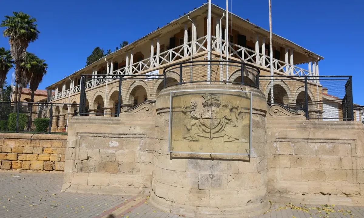 Protective panel over British royal coat of arms at old Nicosia courts remains broken